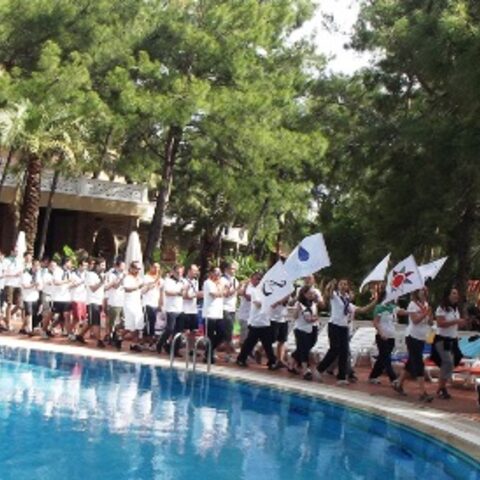 Havuz kenarında bayraklarla yürüyen katılımcılar