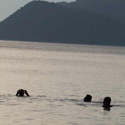 Gün batımında denizde yüzen katılımcılar